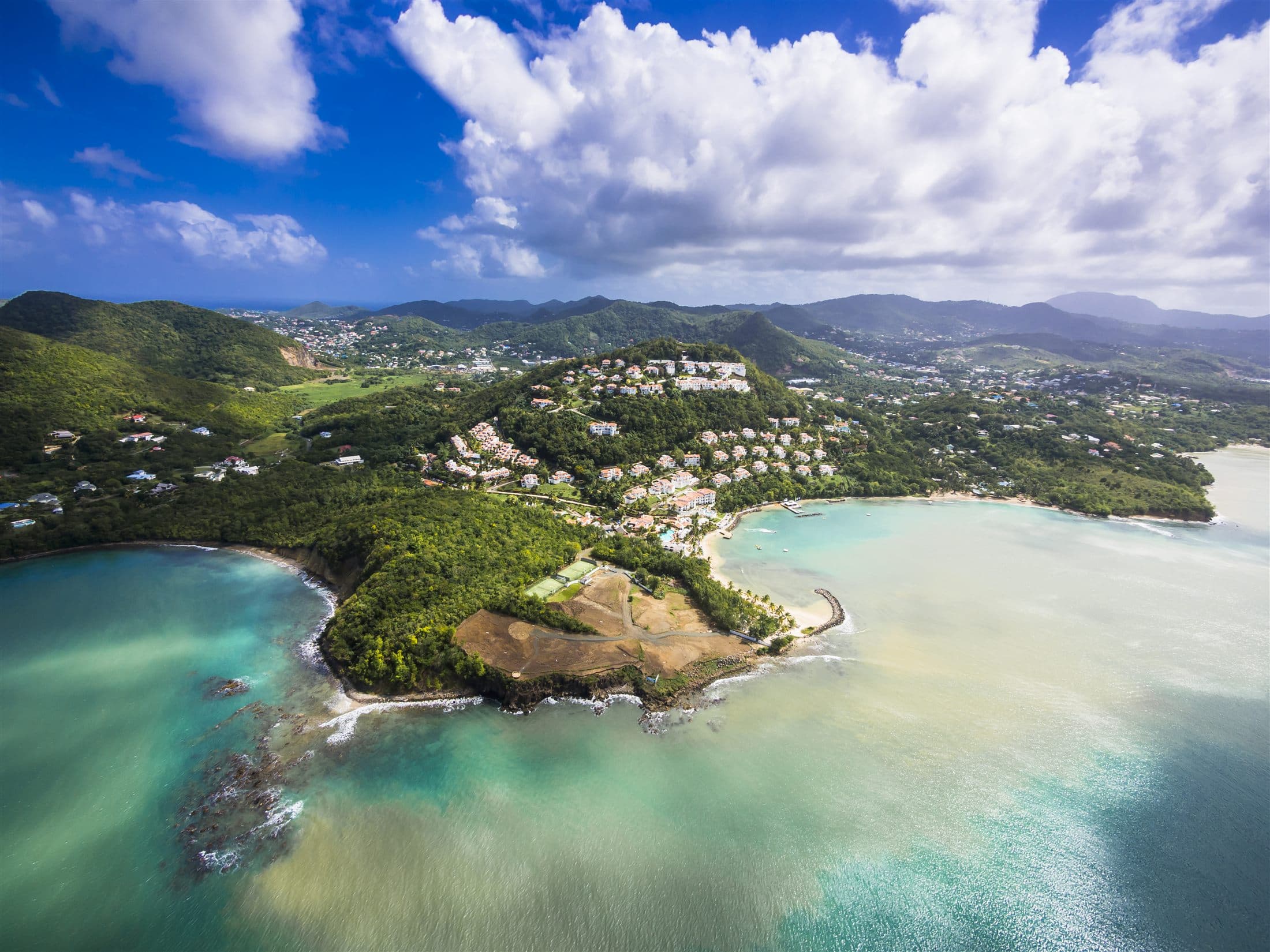 Aerial view of St Lucia's coastline with a crescent bay and tropical greenery.
